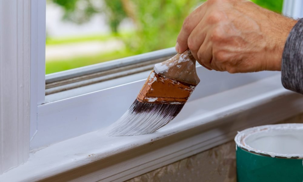 Painting a wooden window paint with paintbrush while painting window trim