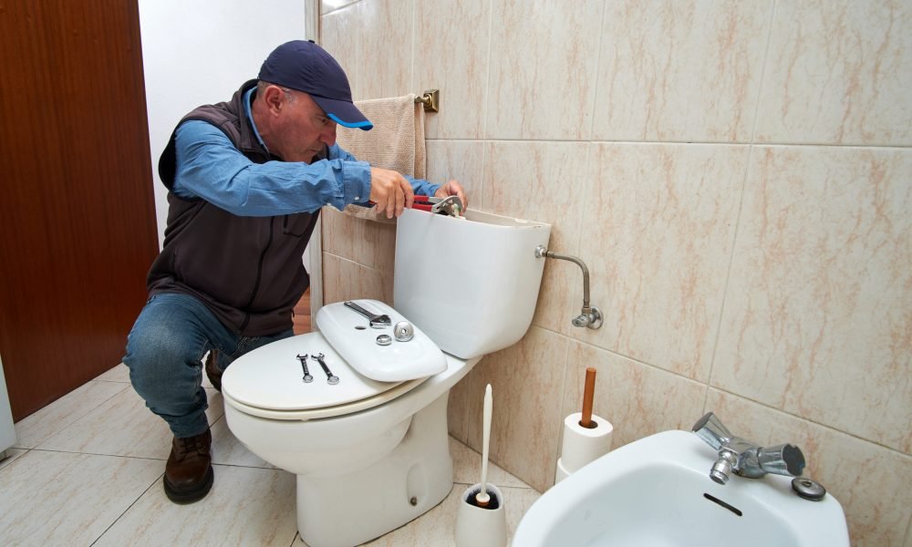 Professional plumber repairing a toilet cistern